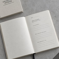 Cream Gratitude Journal open on a cool grey surface